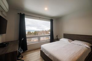 a bedroom with a bed and a large window at Complexe la Falaise in Rivière-du-Loup