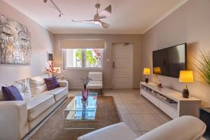 a living room with a white couch and a flat screen tv at Only 350 yards from Eagle Beach! in Palm-Eagle Beach