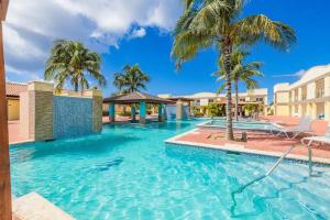 a swimming pool with palm trees in a resort at Only 350 yards from Eagle Beach! in Palm-Eagle Beach
