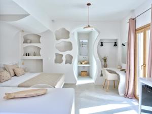 a white bedroom with a bed and a desk at Rocaia Mini Suites Naousa in Naousa