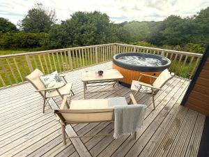 a deck with a hot tub and chairs and a table at Byrnside Lodge & NEW HOT TUB in Latheron