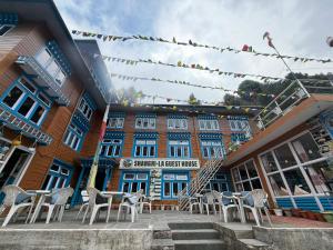 a building with tables and chairs in front of it at Shangri-la Guest House in Phakding