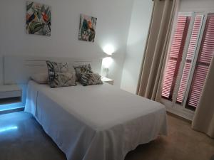 a white bed with pillows on it in a bedroom at Feel The Vibe Alcaidesa in La Alcaidesa