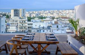 ein Holztisch auf einem Balkon mit Blick auf eine Stadt in der Unterkunft ONOMA Hotel in Thessaloniki