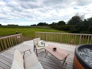 a deck with a hot tub and two chairs and a table at Byrnside Lodge & NEW HOT TUB in Latheron