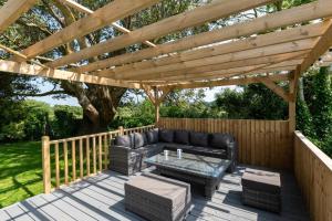 a wooden deck with a couch and a wooden pergola at 3 Bed in Llanfairpwllgwyngyll oc-wai194 in Dwyran