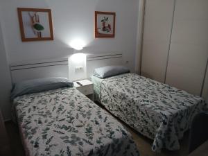 two beds in a small room with a lamp at Feel The Vibe Alcaidesa in La Alcaidesa +28 photos
