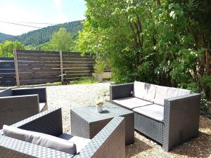 a patio with two couches and a table and a fence at Cap Vosges 3 étoiles, Jeux et Balnéo, entre Vosges et Alsace in Plainfaing