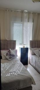 a bedroom with two beds and two windows at appartement forêt diplomatique in Tangier