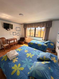 ein Schlafzimmer mit zwei Betten und einem Tisch mit Fernseher in der Unterkunft City Hotel in Cochabamba