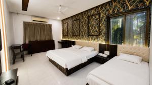 a hotel room with two beds and a window at Star resort in Bhusāwal