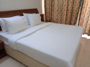 ein Bett mit weißen Laken und Kissen in einem Zimmer in der Unterkunft Private flats in Salalah