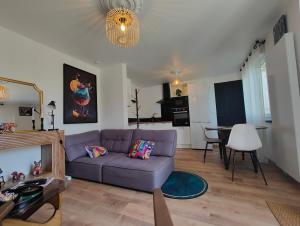 a living room with a purple couch and a table at Maison chic & chill in Saint-Brieuc
