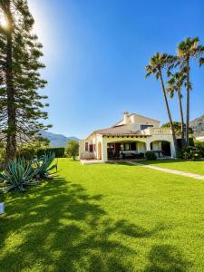 a house with palm trees and a green lawn at Can Brenno in Port de Pollensa