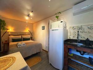 a small room with a bed and a refrigerator at Tiny House Passaúna - Climatizado, parque e deck in Curitiba
