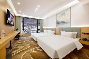 a hotel room with two beds and a desk at 四川思睿博酒店 in Heishui