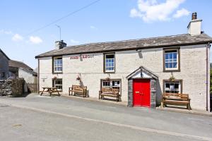 a white brick building with a red door and benches at Charcoal House in Coniston
