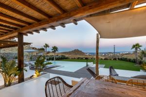 an outdoor patio with a table and chairs and a pool at Villa RED VENUS in Kalafatis