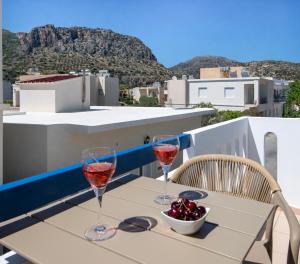 two glasses of wine on a table on a balcony at Petra Studios in Palaiochora
