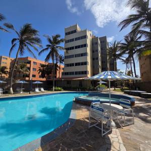a swimming pool with a table and chairs and a building at Tucacas, Frente al Mar, Piscina y Playa Privada in Tucacas