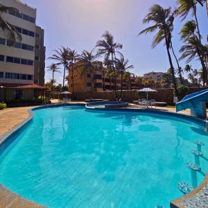 a large swimming pool with palm trees and a building at Tucacas, Frente al Mar, Piscina y Playa Privada in Tucacas +25 photos