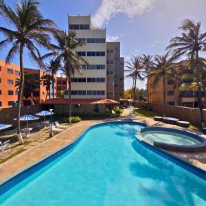 a large swimming pool with palm trees and a building at Tucacas, Frente al Mar, Piscina y Playa Privada in Tucacas