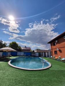 a swimming pool in a yard with chairs and a building at Pensiunea Bianca in Corbu