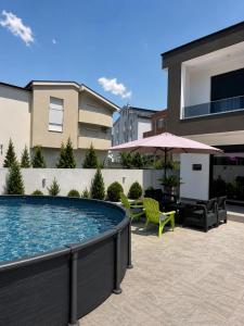 a swimming pool with a table and chairs and an umbrella at Villa Hana in Bar