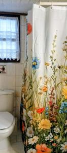 a bathroom with a shower curtain with flowers on it at Phedra's House Spata- Artemida in Artemida +40 photos
