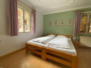 a bedroom with a bed with white sheets and two windows at Villa Zeppelin - App Bergkristall in Bramberg am Wildkogel +15 photos