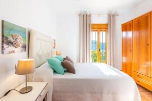 a white bedroom with a bed and a table with a lamp at Casa Mari in Almogía +22 photos