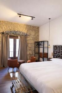 a bedroom with a large white bed and chairs at Apartamentos El Capitan in Potes