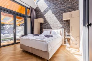 a bedroom with a bed and a large window at Elite House Platina Apartment in Leányfalu