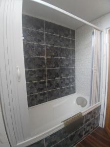 a bathroom with a shower with a tile wall at Petit bien in Marcillac +5 photos