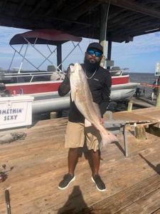 a man standing on a dock holding a fish at Come Friday Cottages in Bacliff