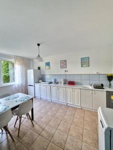 a large kitchen with white cabinets and a table at Rodzinny dom w Rożnowie Duży Ogród i Zabawki in Rożnów