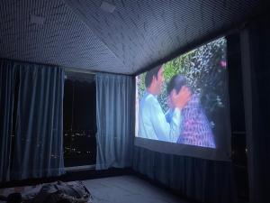 a room with a large screen with a couple kissing at Countryside Retreat in Pune