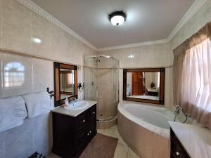 a bathroom with a tub and a sink and a bath tub at Castelo Sutil Guest House in Bloemfontein