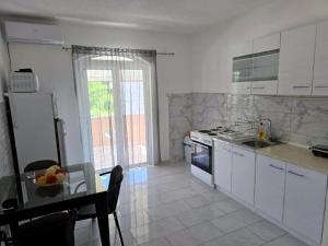 a kitchen with white cabinets and a table with a tableablish at Vila Cattleya in Donji Štoj