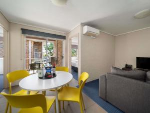ein Wohnzimmer mit einem Tisch und gelben Stühlen in der Unterkunft ibis Styles Canberra in Canberra