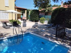 a pool with chairs and an umbrella next to a house at Dee's House and Pool in Labin