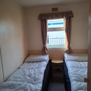 two beds in a small room with a window at Atlas Florida in Ingoldmells