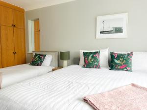 two beds in a bedroom with white sheets and green pillows at Ivy Guesthouse in Kilkenny
