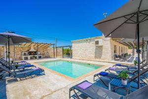 a swimming pool with chairs and an umbrella at Villa Casa Liveris by Villa Plus in Akrotiri