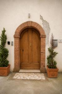a wooden door in a brick wall with two plants at Merus in Faicchio