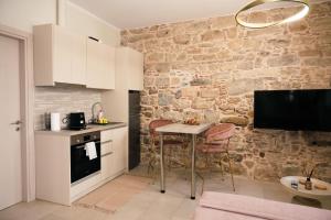 a kitchen with a table and a stone wall at Kallia Castle apartments in Chios