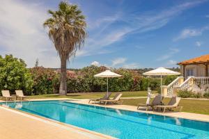 a swimming pool with chairs and umbrellas next to a house at Villa Polymnia in Kaligata