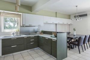 a kitchen with white cabinets and a table with chairs at Villa Agnandi in Lakíthra