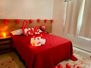 a bedroom with a red bed with a love sign on it at Hotel Coutinho in Pirapora