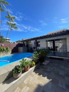 a villa with a swimming pool and palm trees at Casa Cris cabo frio in Cabo Frio